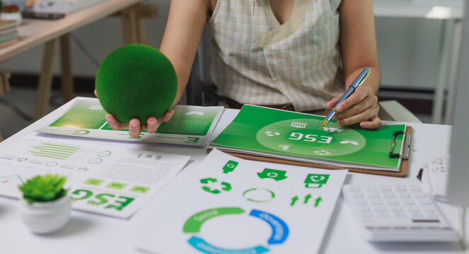 Woman holding green sphere analyzing esg reports