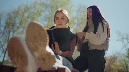 collaborative review of manuscript in peaceful springtime setting, asian editor and white author engaging in manuscript discussion under shade of trees during serene spring sunlight