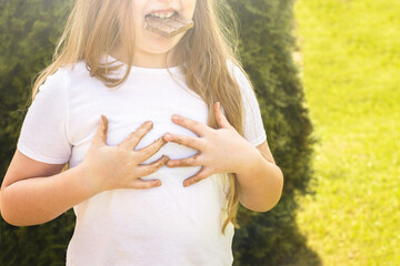 Girl child staining her white t-shirt with stain while enjoying a delicious chocolate bar in garden