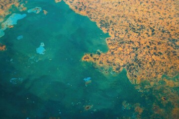 Abstract texture of rust and turquoise corrosion forming organic shapes on a metal surface, creating a vivid blend of colors and natural patterns.