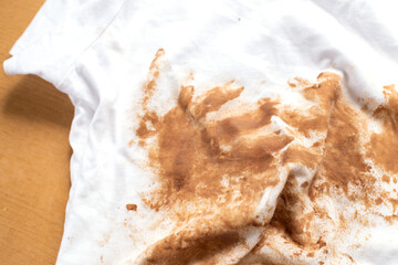 Dirty stains covering white t-shirt lying on wooden table