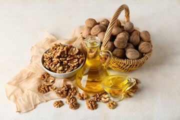 Tasty walnuts with jug and gravy boat of oil on light grunge background