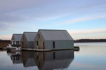 A beautiful view of a lake with water houses and sunrise under a cloudy sky
