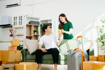 Obraz premium Capture the essence of moving day with a smiling couple unpacking boxes in a bright, cozy living room.