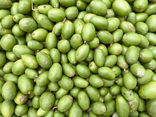 Unripe green mangoes tightly packed with stems in market display