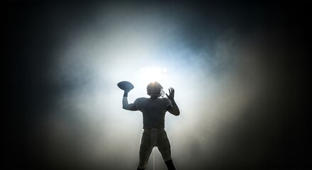 Silhouette of Quarterback Throwing Football in Spotlight.