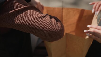 friends examining arts and crafts items outdoors, pair of friends exploring small art objects in park, two companions searching for creative supplies on bench during lively park activity