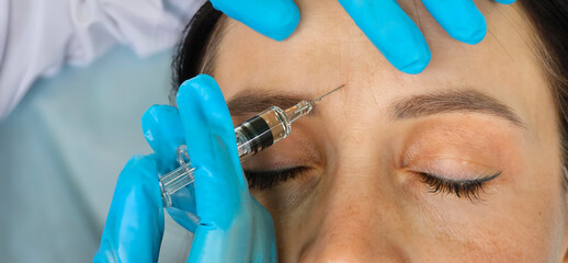 Woman Receiving Forehead Botox Injection In Clinic