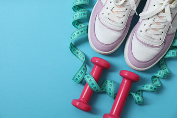 Scales, sneakers, dumbbells and measuring tape on a blue background
