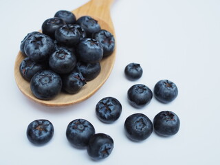 Mulberries placed in a wooden spoon on a white background. Healthy fruit.