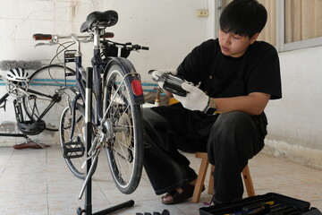 Authentic young tomboy repairing a flat bicycle tire in a garage. Independent female mechanic fixing a bike wheel with tools. DIY maintenance and empowerment concept.