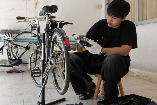 Authentic young tomboy repairing a flat bicycle tire in a garage. Independent female mechanic fixing a bike wheel with tools. DIY maintenance and empowerment concept.