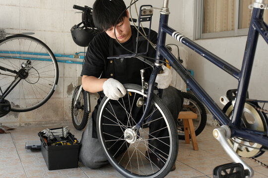 Authentic young tomboy repairing a flat bicycle tire in a garage. Independent female mechanic fixing a bike wheel with tools. DIY maintenance and empowerment concept.