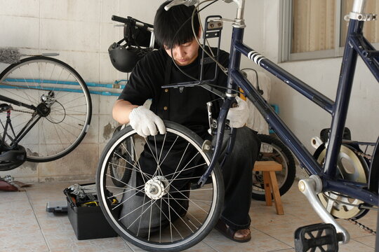 Authentic young tomboy repairing a flat bicycle tire in a garage. Independent female mechanic fixing a bike wheel with tools. DIY maintenance and empowerment concept. - Powered by Adobe