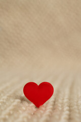 A small red heart decoration sits prominently on a warm, textured background. This charming scene evokes love and warmth, ideal for Valentine's day digital projects.