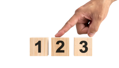 A hand selects the number two on wooden blocks numbered one through three against black