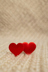 Two red heart decorations sit closely together on a soft, textured fabric background. This simple yet romantic setup is ideal for digital content related to love and Valentine's Day.