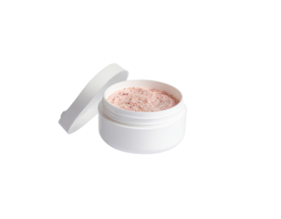 Open container of pink bath salt with a textured surface and a partially unscrewed lid showing the product inside