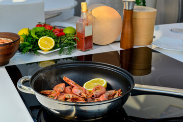huge shrimps being cooked on a griddle in the kitchen at home