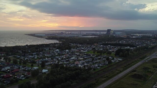 Birds eye aerial view of &Ouml;stra Stranden, Halmstad&rsquo;s iconic long sandy beach with shallow turquoise water and adjacent modern residential neighbourhood, captured during golden hour.