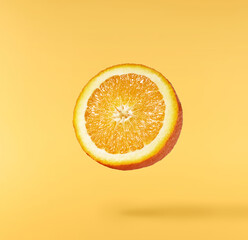 Fresh juicy orange slices floating on a vibrant yellow background. Creative citrus levitation...