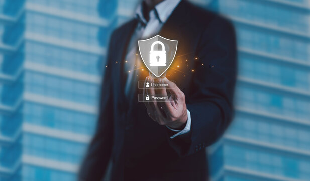 A businessman touching a glowing security shield with username and password fields representing cybersecurity digital authentication, secure access and data protection in modern business environments.