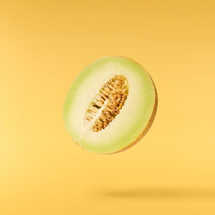 Fresh ripe Galia Melon falling in the air isolated on yellow background