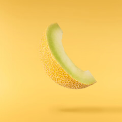 Fresh ripe Galia Melon falling in the air isolated on yellow background