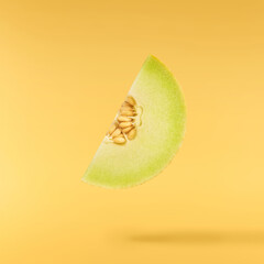 Fresh ripe Galia Melon falling in the air isolated on yellow background