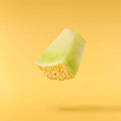 Fresh ripe Galia Melon falling in the air isolated on yellow background