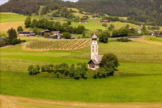 Aerial drone view of St. Valentin church surrounded farm fields in Dolomites Alpe di Suisi. South Tyrol, Italy