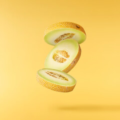 Fresh ripe Galia Melon falling in the air isolated on yellow background