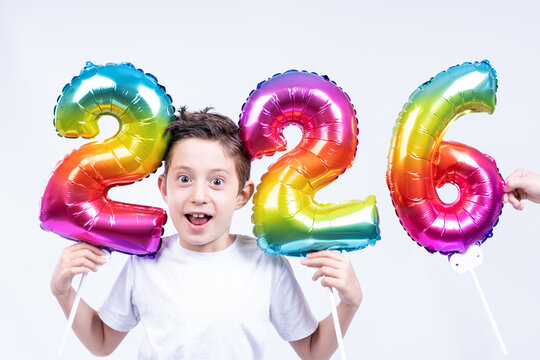 A little boy holds colorful balloons showing the coming new year 2026