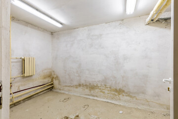 Old Basement Room with Worn Walls and Heating Pipes