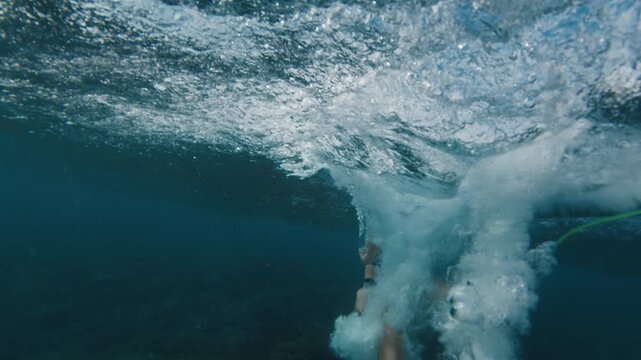 Beginner woman surfer rides the barrelling ocean wave in the Maldives. In water and underwater view of the surfer on the wave