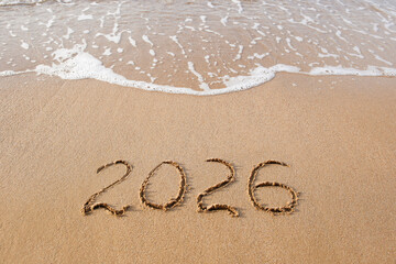 The inscription 2026 on the sand by the sea. Happy New Year.