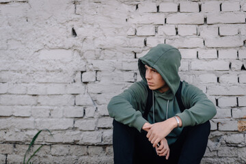 Young man feeling sad and lonely against brick wall