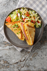 One Pan Breakfast Sandwich is the ultimate hack for busy mornings with egg, ham and cheese closeup on the plate on the table. Vertical top view from above
