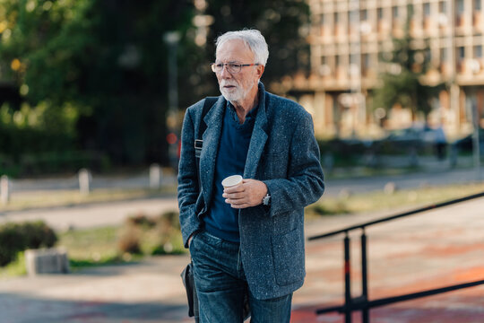 Senior man walking with coffee contemplating urban life