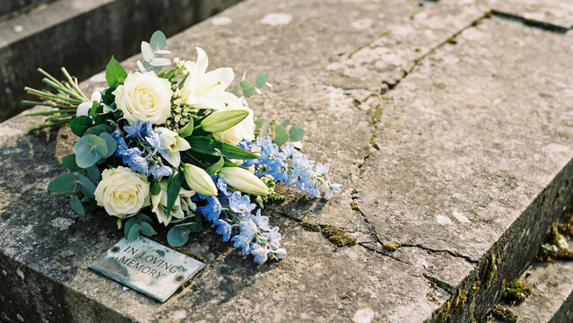 Flower bouquet placed on weathered gravestone in quiet cemetery