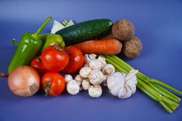 Various vegetables are laid out on the table: celery, carrot, cucumber, tomato, potato, mushrooms,...