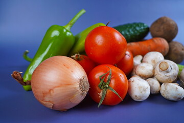 Various vegetables are laid out on the table: celery, carrot, cucumber, tomato, potato, mushrooms,...