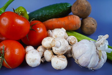 Various vegetables are laid out on the table: celery, carrot, cucumber, tomato, potato, mushrooms,...