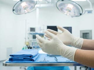 Hands donning sterile gloves in an operating room preparation