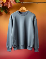 Stylish Gray Sweatshirt Hanging with Autumn Leaves on Branch Against Warm Backdrop
