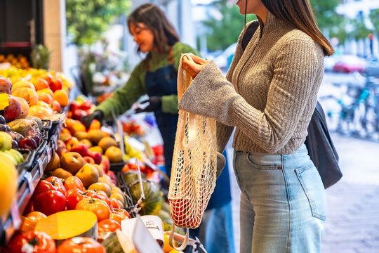 Woman shopping fresh organic produce using reusable mesh bag