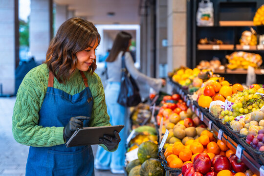 Woman checking fruit inventory in a grocery store using a tablet