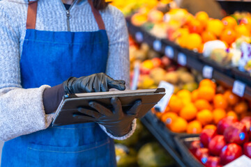 Grocery store worker checking produce inventory with tablet