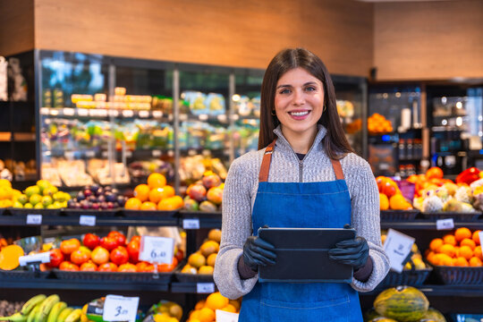 Female greengrocer managing inventory with tablet in supermarket