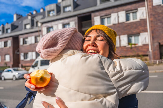Mother and child embracing with an apple in urban street